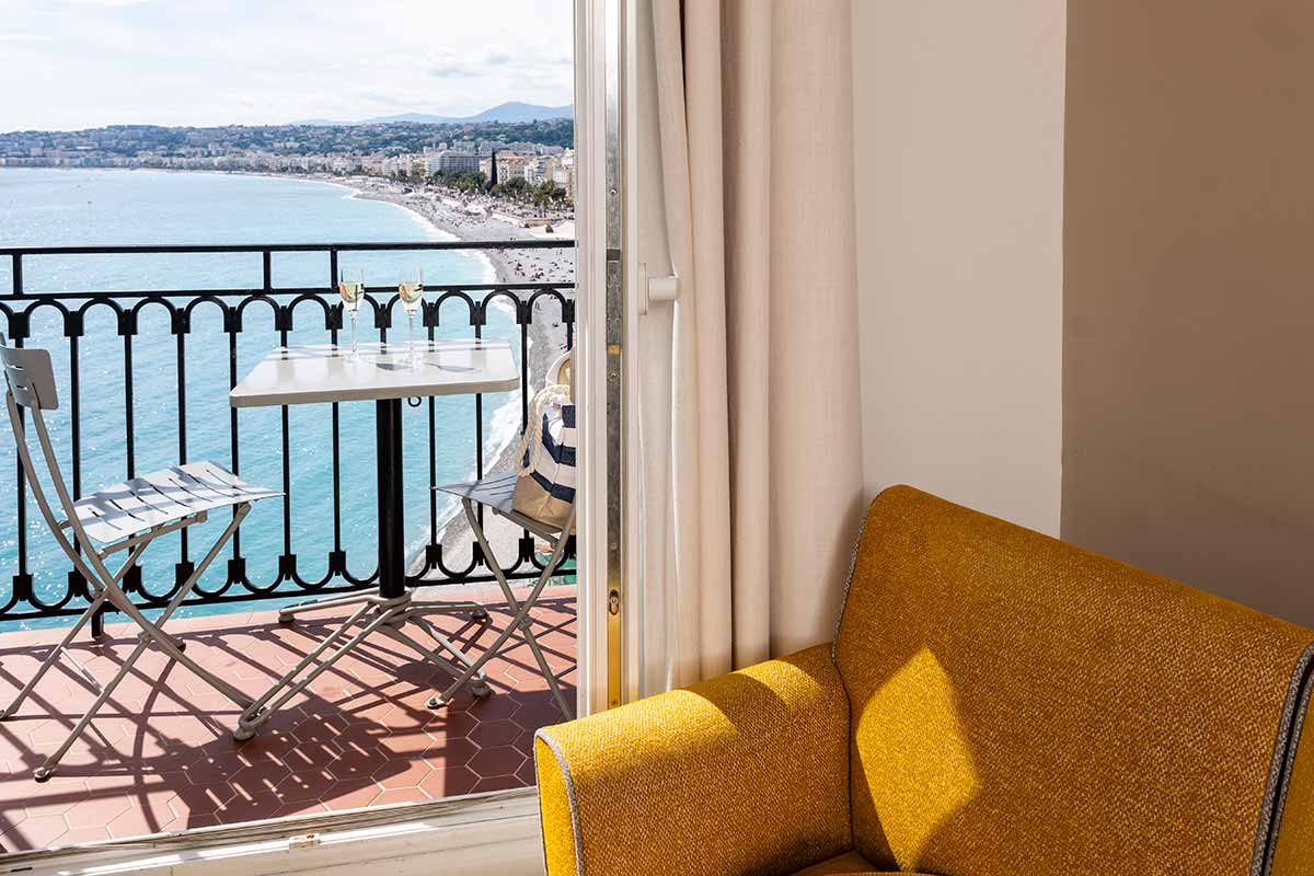 Small balcony with a table and chairs overlooking the Bay of Angels at Hôtel Suisse