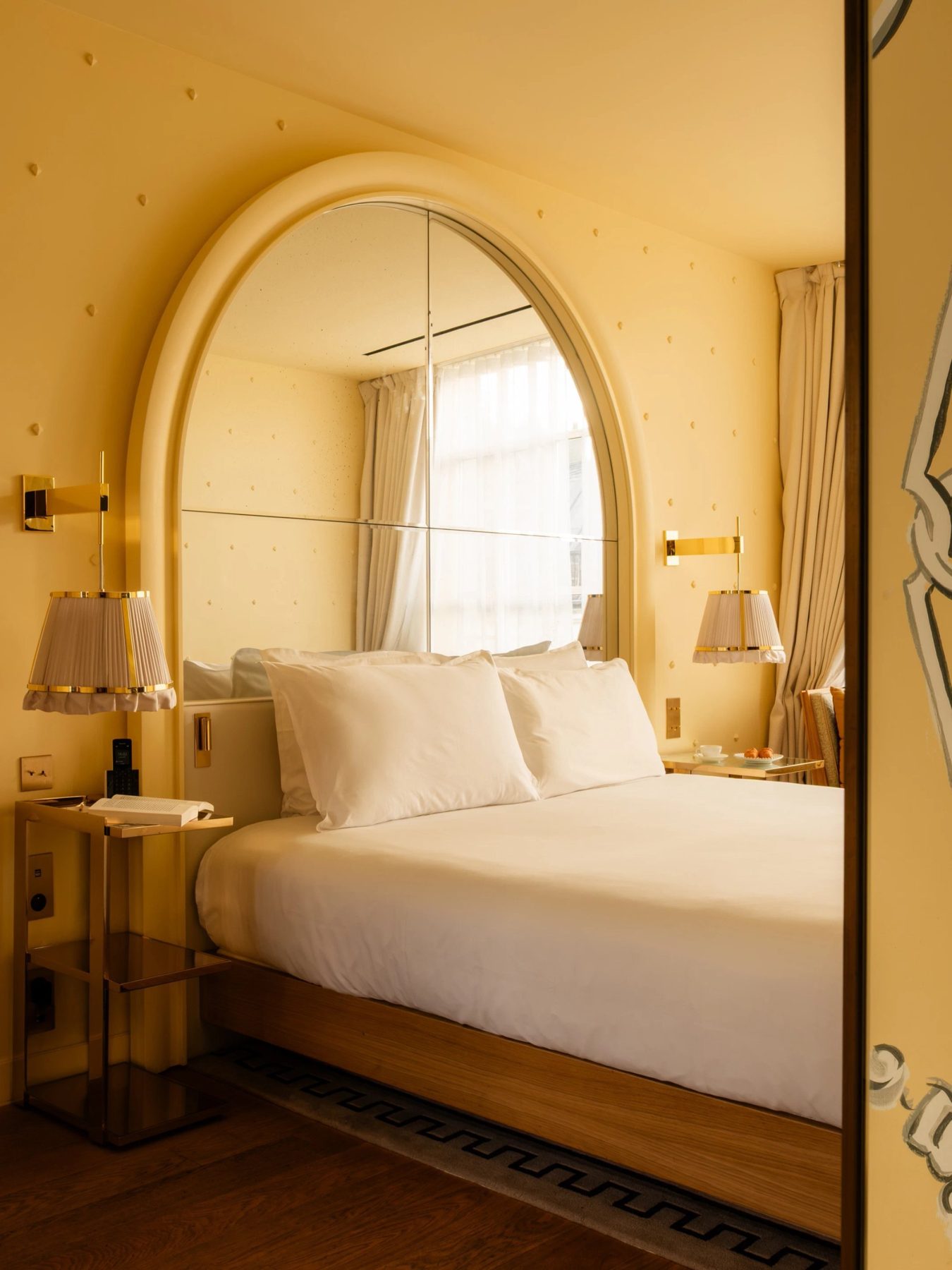 Cream bedroom with an oval mirror and bedside lamps at 9Hôtel Confidentiel.