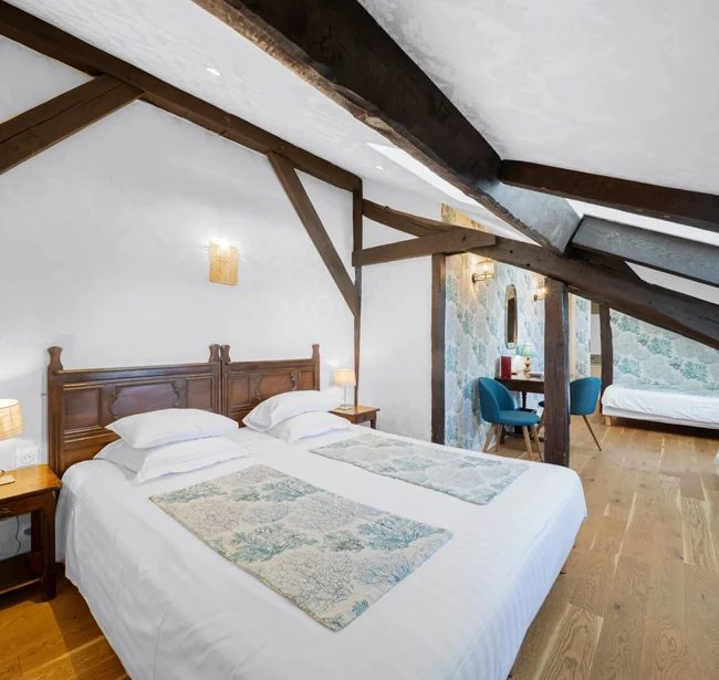 Beds beneath exposed beams in a Family room at Hôtel de la Bretonnerie.