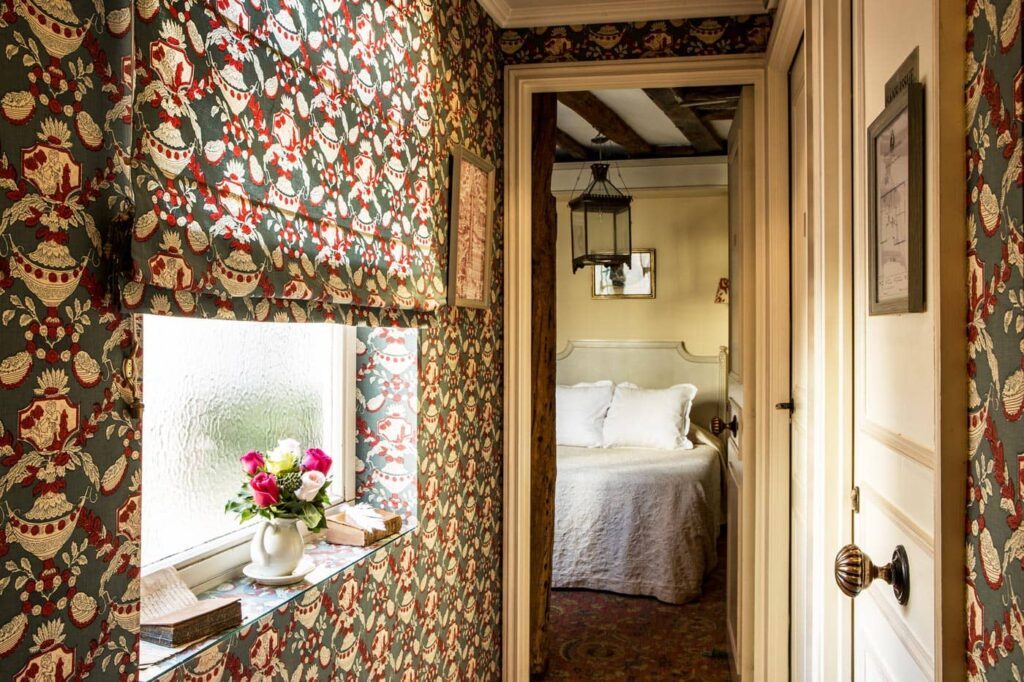 Floral-papered passage opening to a bed at Hôtel Caron de Beaumarchais.