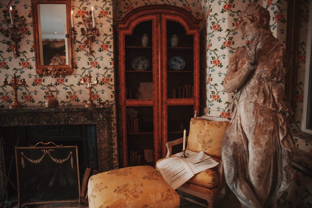Fireplace, painted cabinet and antique-style chairs at Hôtel Caron de Beaumarchais.