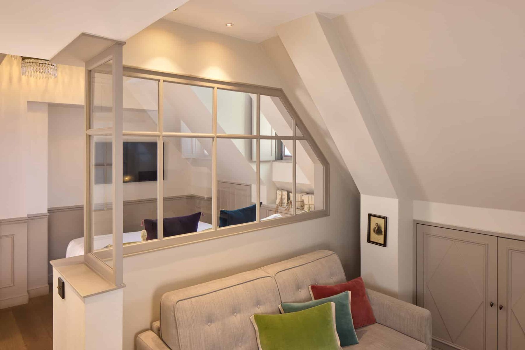 Sofa and glazed partition with a bed beyond in Hôtel Charles V’s Junior Suite.