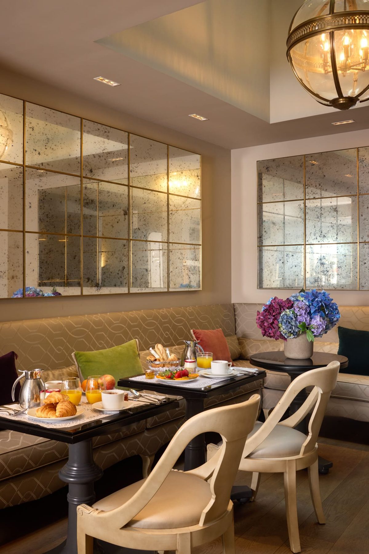 Set tables, upholstered seating and mirrored walls in Hôtel Charles V’s breakfast room.