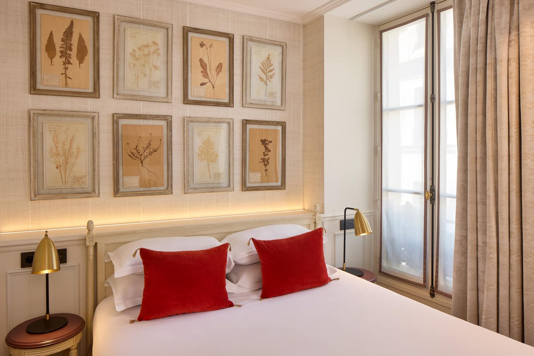 Superior bedroom with red cushions and framed botanical prints at Hôtel Charles V.