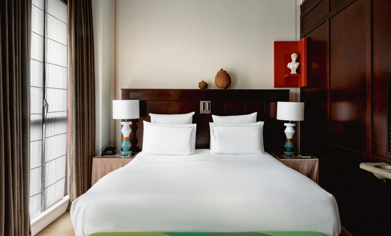 Superior bedroom with white bedding and a dark wood headboard at Experimental Marais.