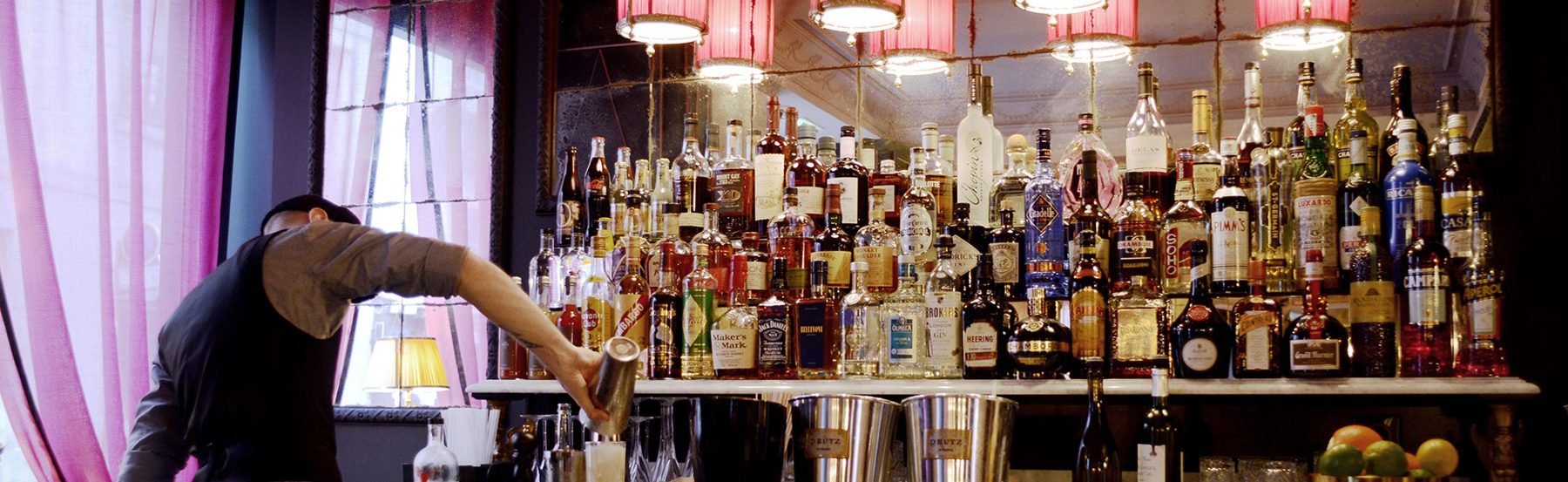 Bottle-lined bar and pink curtains at Hôtel de JoBo.