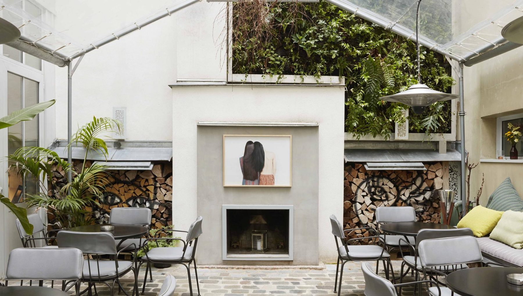 Courtyard tables and chairs around a fireplace at Hôtel Jules & Jim.