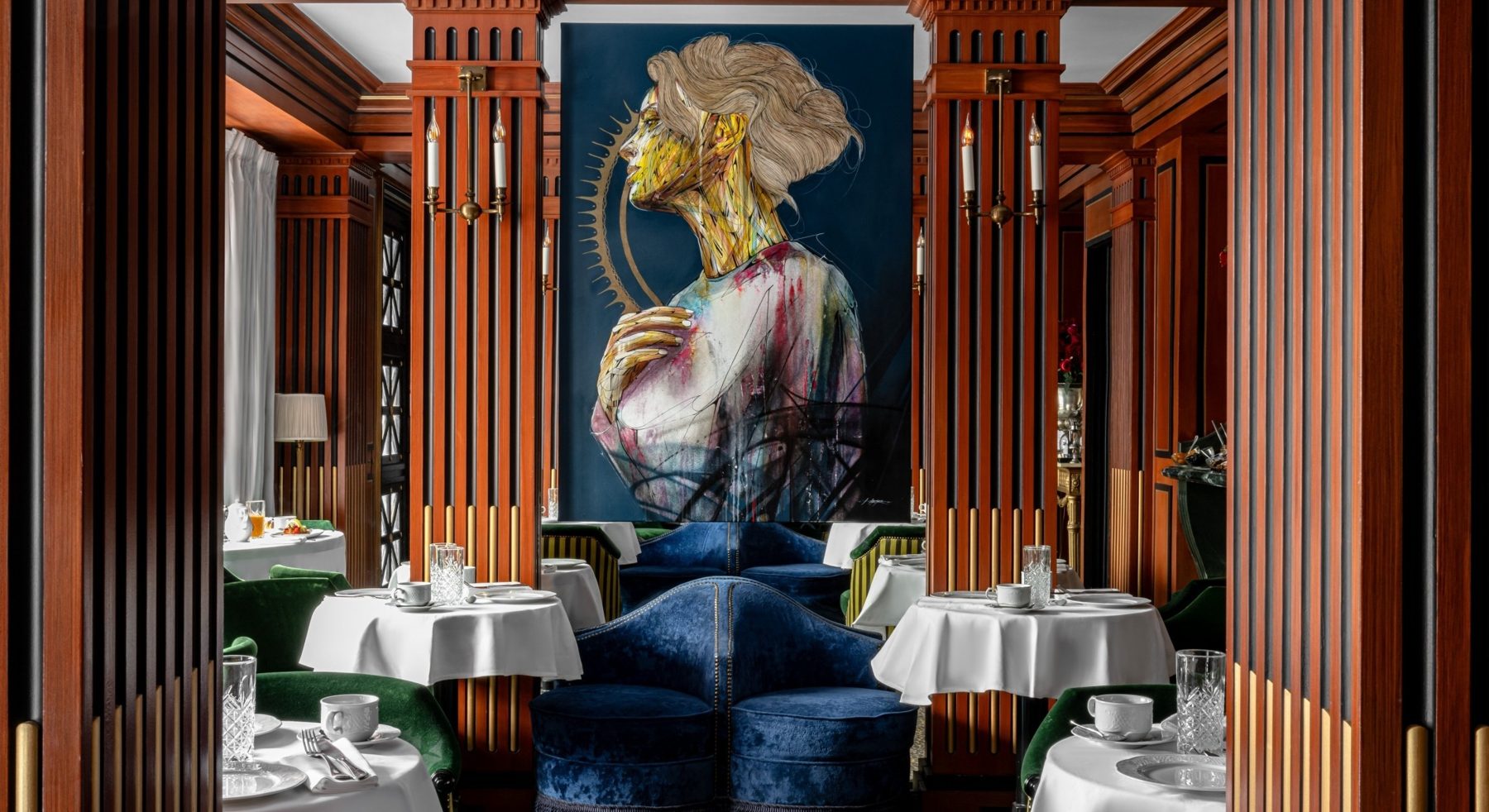 White-clothed tables and blue seats beneath a large portrait at La Chambre du Marais.