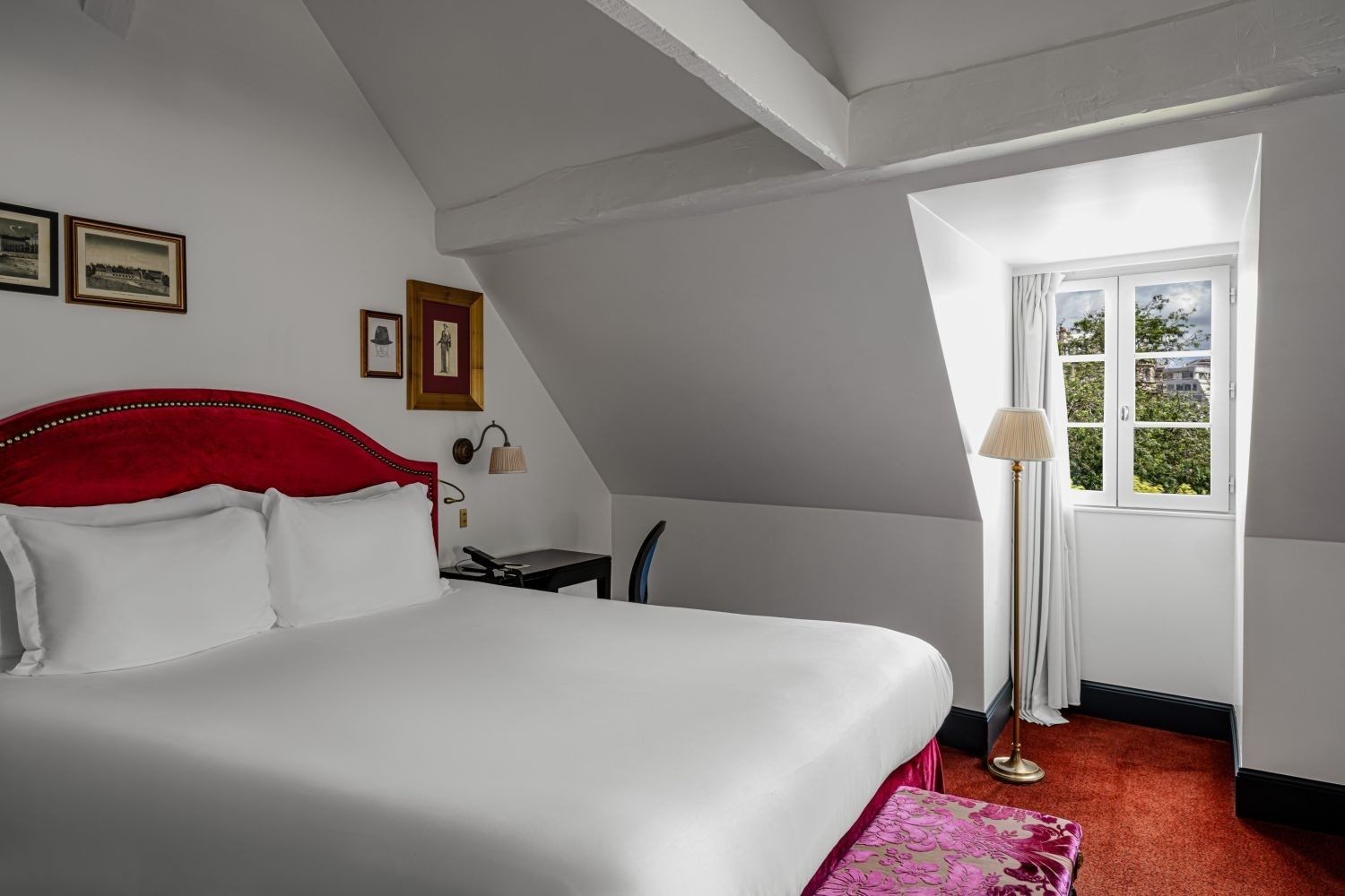 Corner bedroom with a red headboard and exposed ceiling beams at La Chambre du Marais.