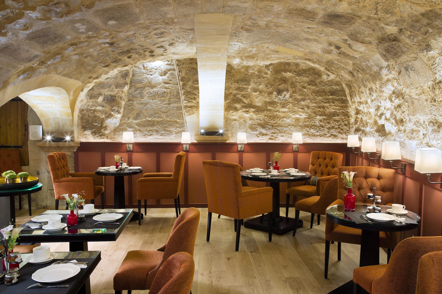 Set tables beneath a stone vault at Les Tournelles.