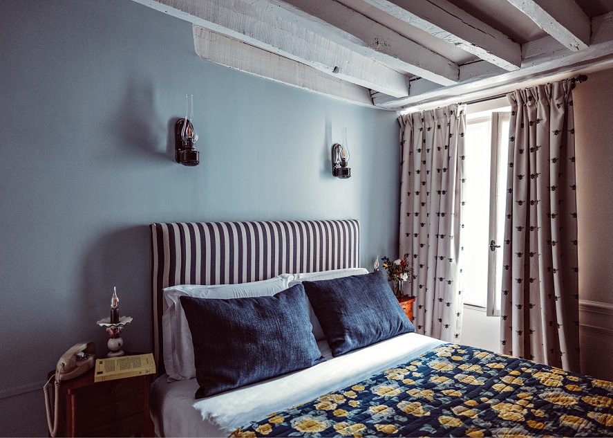 Blue-walled Superior bedroom with striped headboard and ceiling beams at Maison Saintonge.