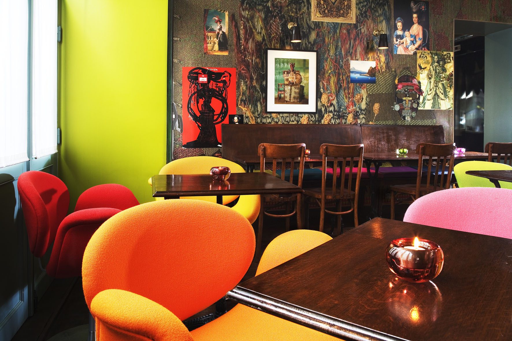 Colourful chairs and dark tables in Hôtel du Petit Moulin’s shared room.