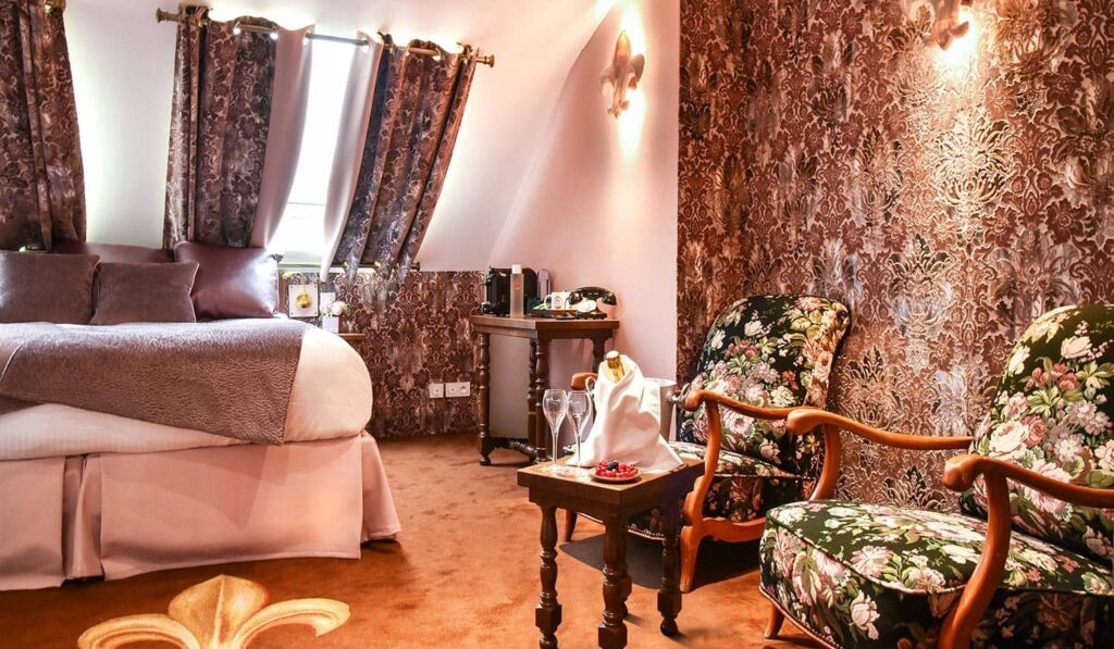 Floral bedroom with beds, chairs and a small table at Le Temple de Jeanne.