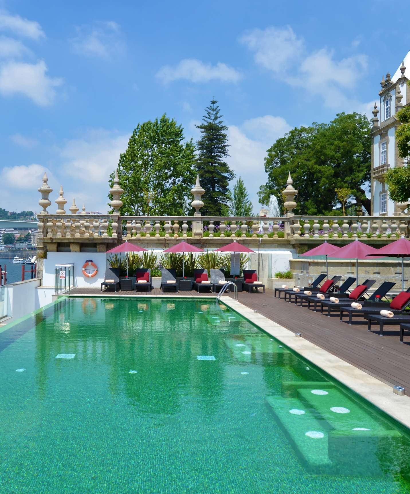 Outdoor pool, loungers, umbrellas and garden planting at Pestana Palácio do Freixo.