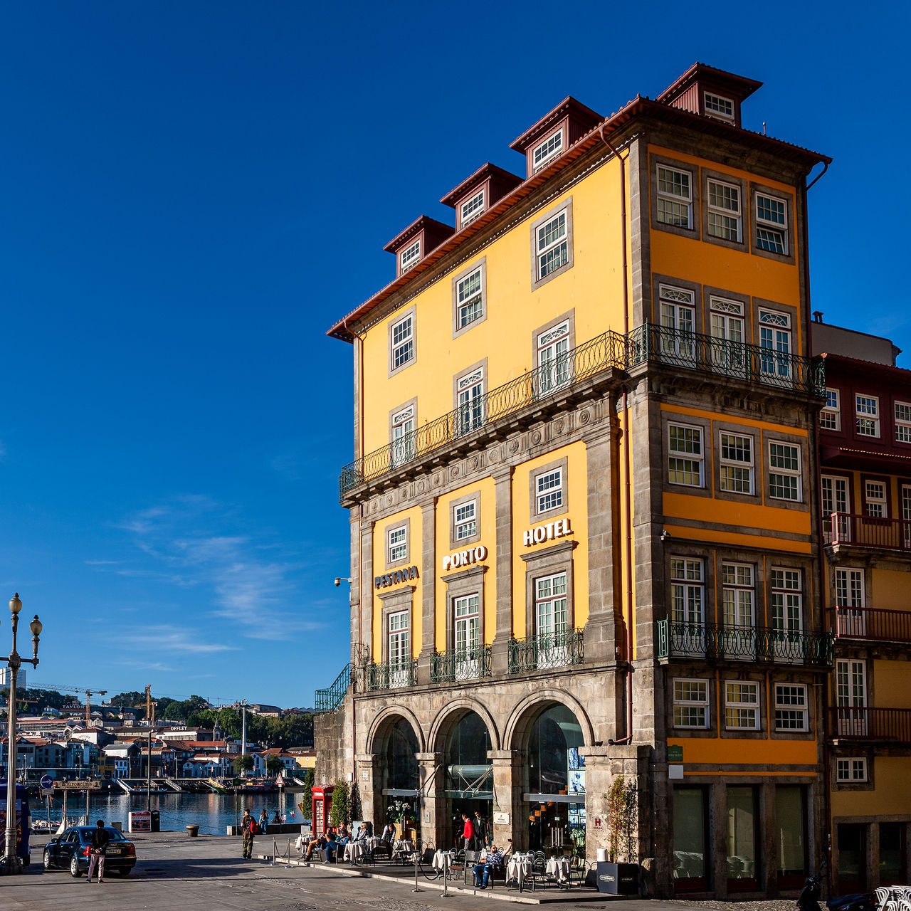 Yellow riverfront facade of Pestana Vintage Porto with balconies and ground-floor arches.