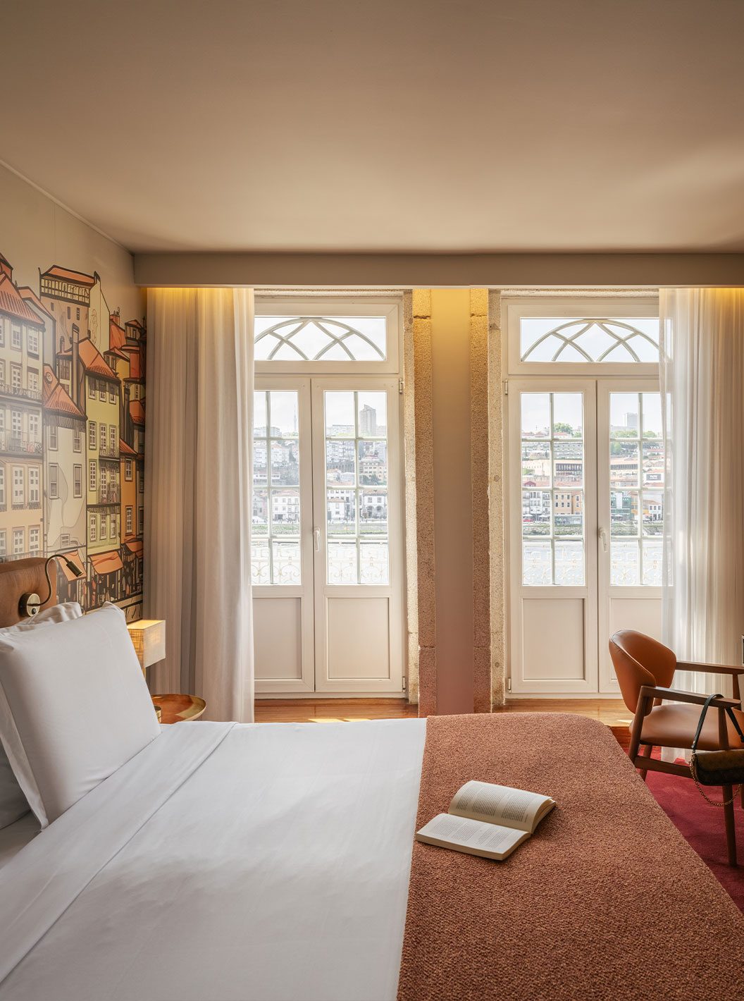 Bed, patterned mural and two glazed balcony doors at Pestana Vintage Porto.