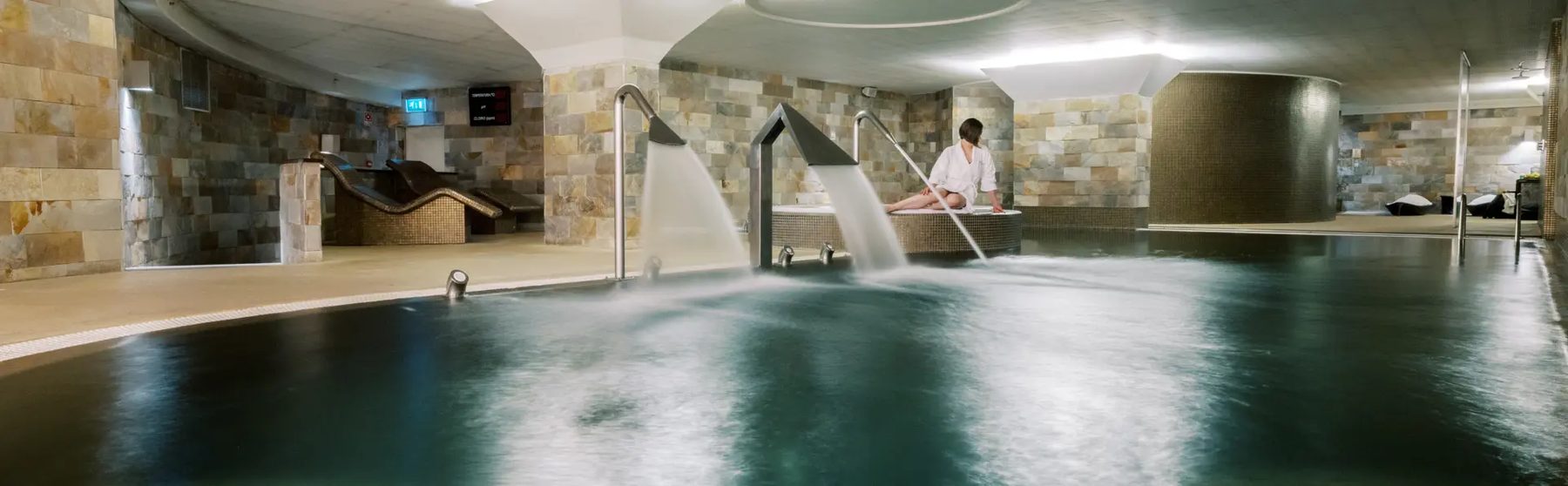 Indoor spa pool with stone walls and water jets at Porto Palácio by The Editory.