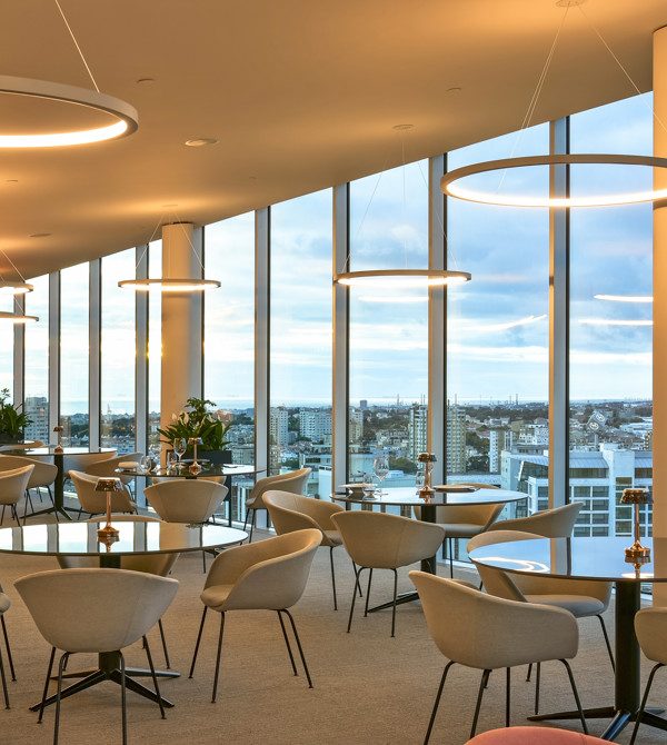 Tables and chairs beside floor-to-ceiling skyline windows at Auge, Porto Palácio.