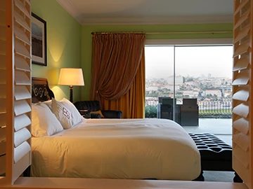 Bed beside floor-to-ceiling terrace doors overlooking Porto at The Yeatman.
