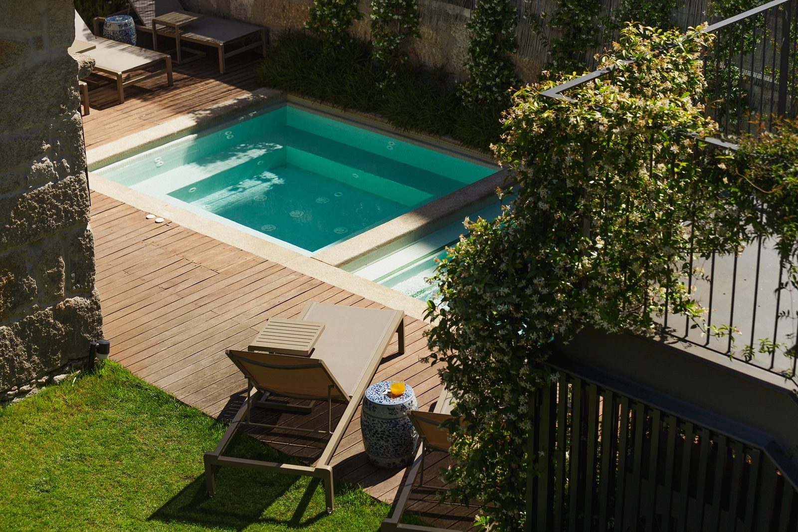 Small outdoor pool bordered by decking, loungers and garden planting at Torel Saboaria.