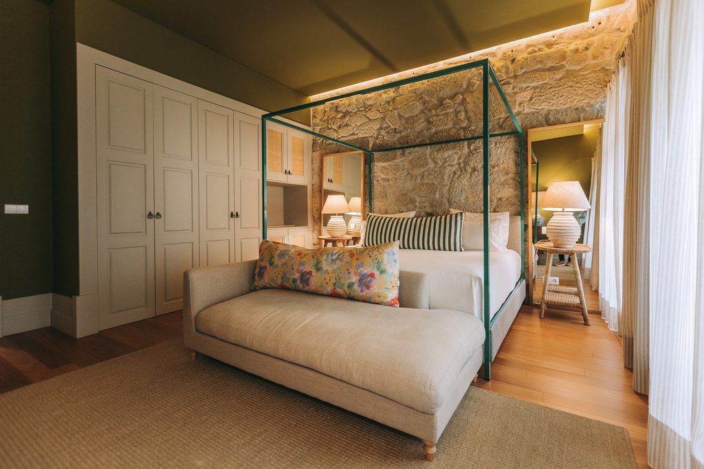 Canopy-style green bed frame beside exposed stonework at Torel Saboaria.