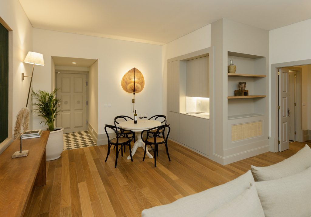 Dining table, sofa edge and white open kitchen shelves in a Torel Saboaria Superior Suite.