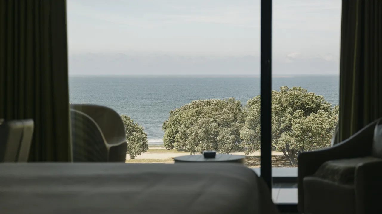 Bed edge and seating beside a window facing the Atlantic at Vila Foz.