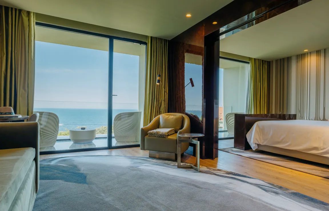 Bedroom and sitting area with glazed balcony doors toward the ocean at Vila Foz.