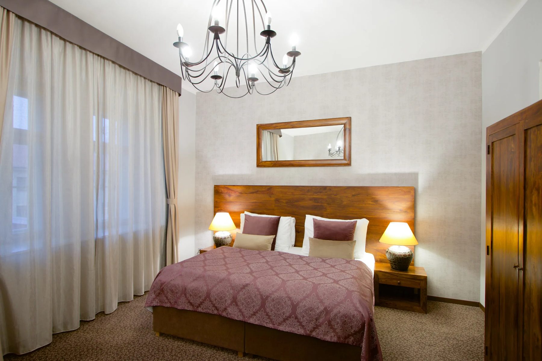 Bedroom with a wooden headboard, double bed and chandelier.
