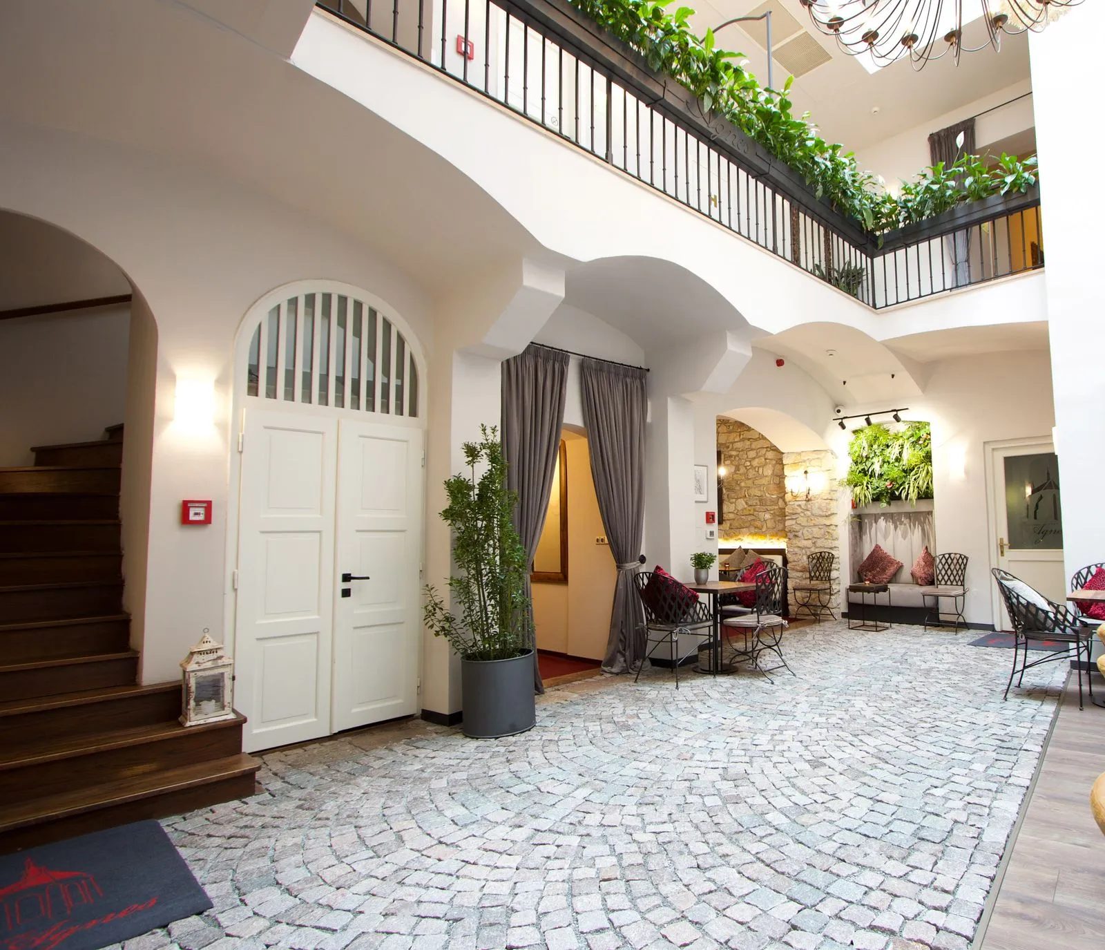 Covered courtyard with stone paving, tables and an upper gallery.
