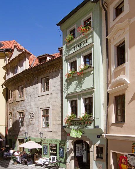 Narrow green hotel facade between neighbouring historic buildings.