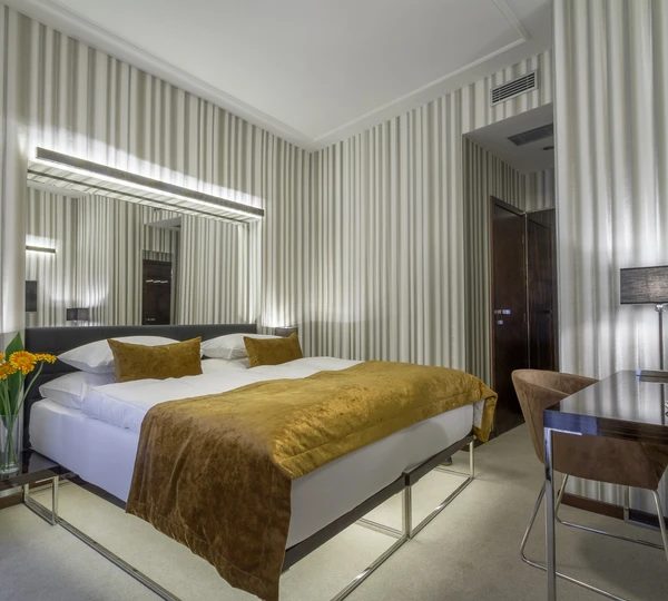 Double bedroom with striped walls, a large mirror and desk.
