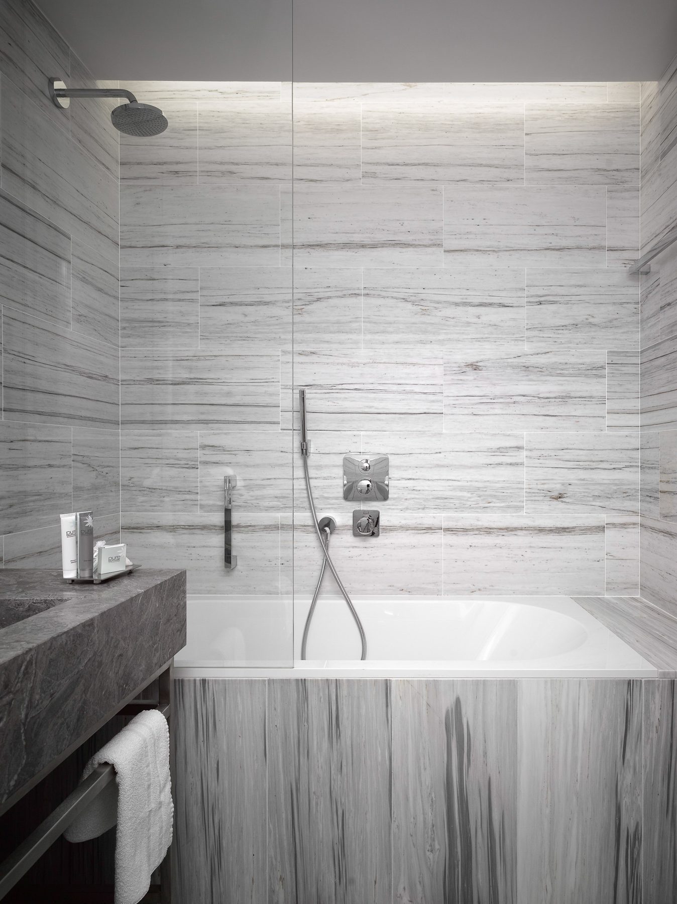 Stone-lined bathroom with a bath and overhead shower.