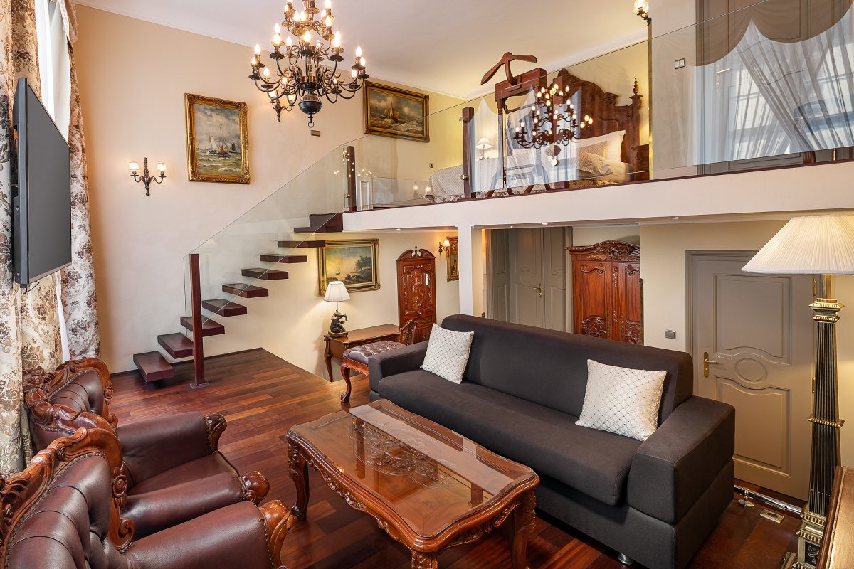 Sofa and coffee table below a mezzanine reached by an open staircase.