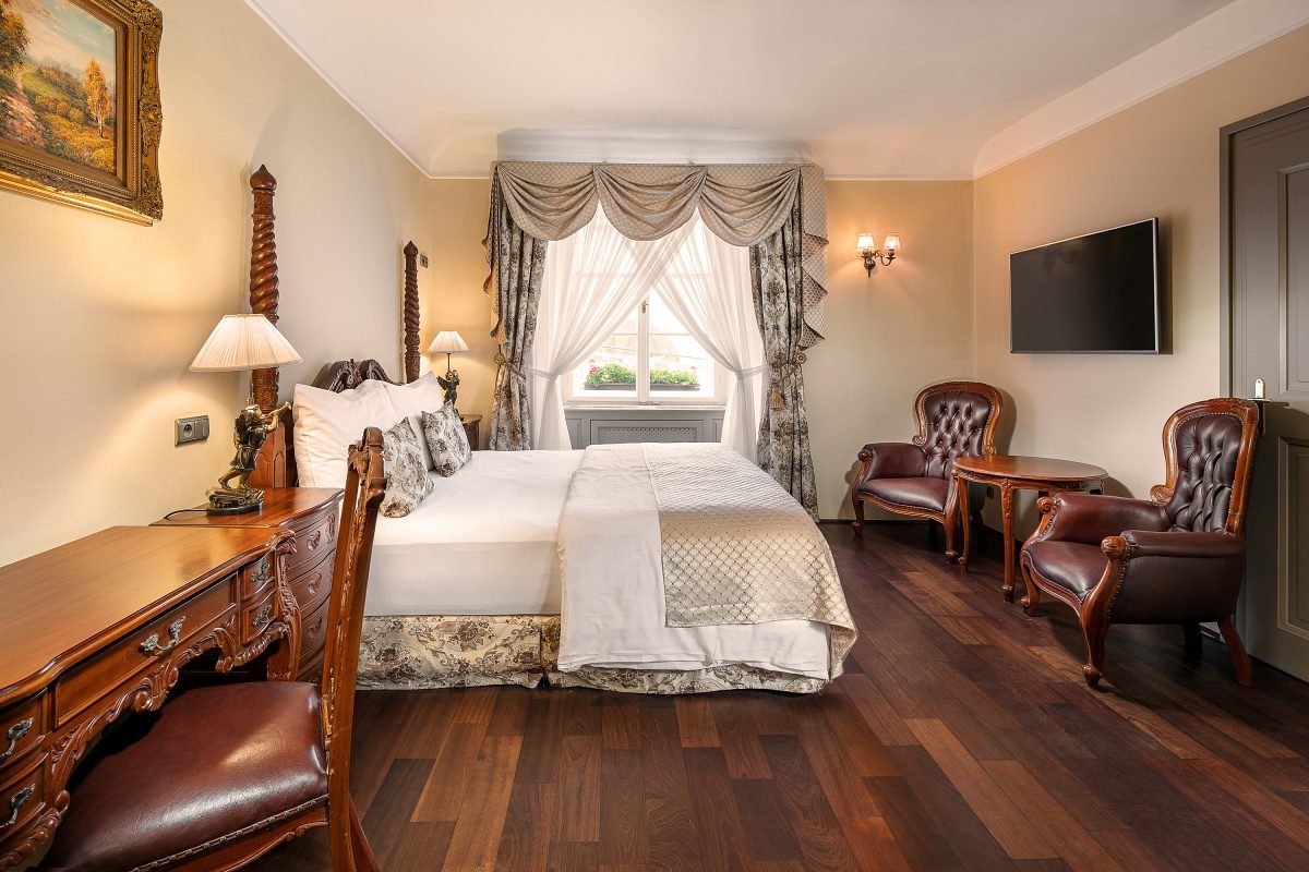 Double bedroom with antique-style furniture, two chairs and a window.