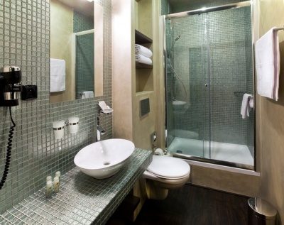 Tiled bathroom with a basin and shower behind a glass screen.