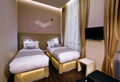 Two separate beds beneath an upholstered headboard in a compact room.