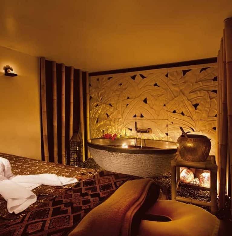 Warmly lit treatment room with a massage bed and patterned walls.