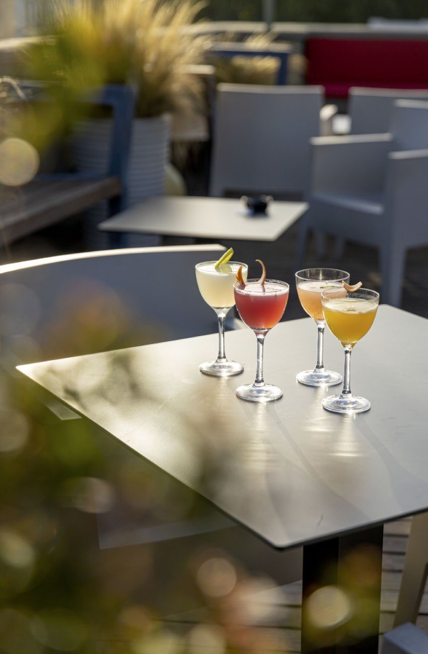 Three cocktails on a table among outdoor chairs at Hotel San Francesco.