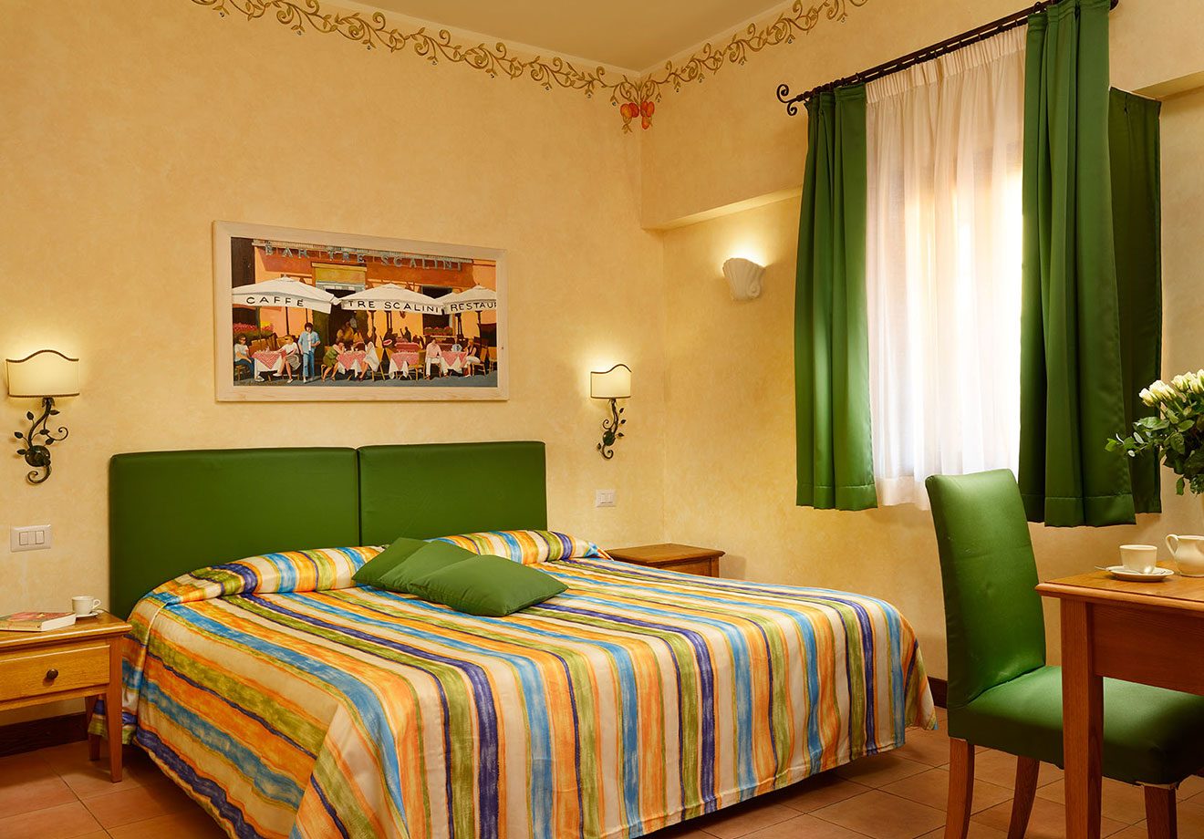 Superior Double bedroom with green headboard, striped bedcover and curtained window.