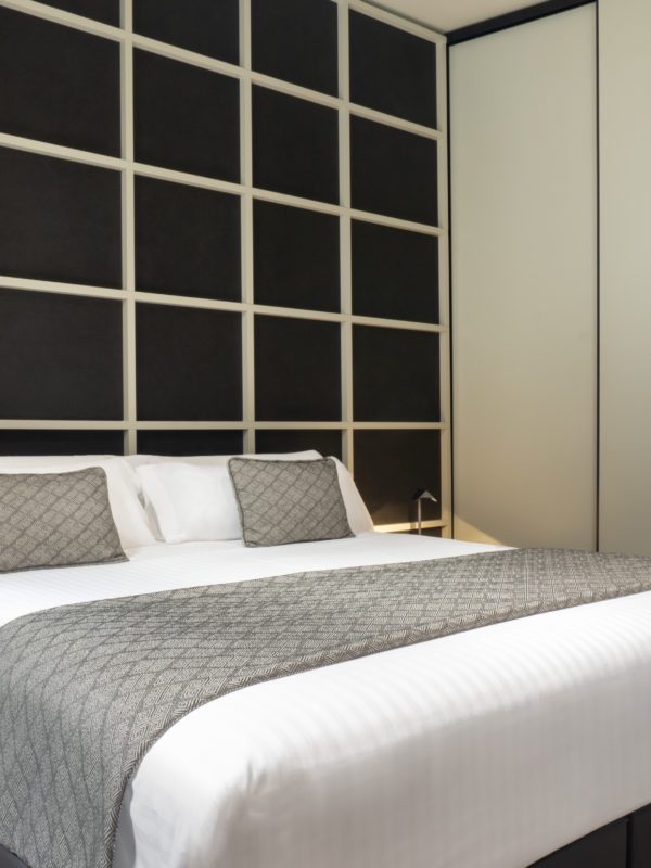 Bed with a grey runner and a dark panelled headboard in a Cabillers Superior Double.