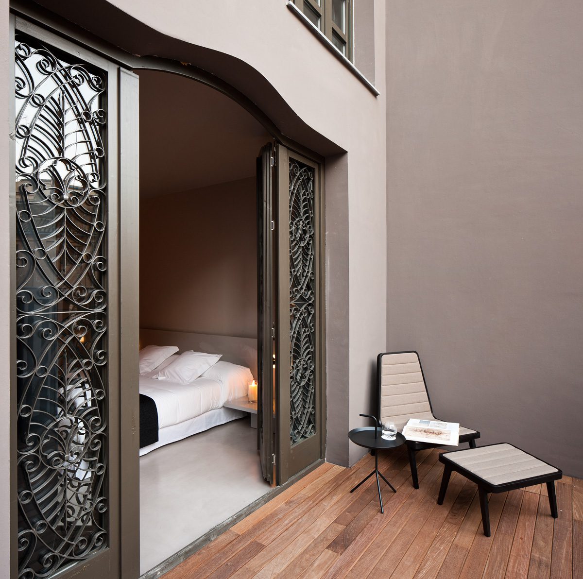 Decked terrace with two chairs, a small table and open doors into the bedroom.