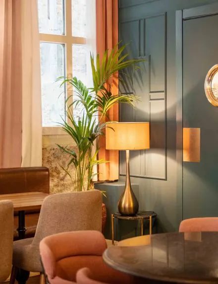 Pink chairs, a round table, a brass lamp and planting at Helen Berger.