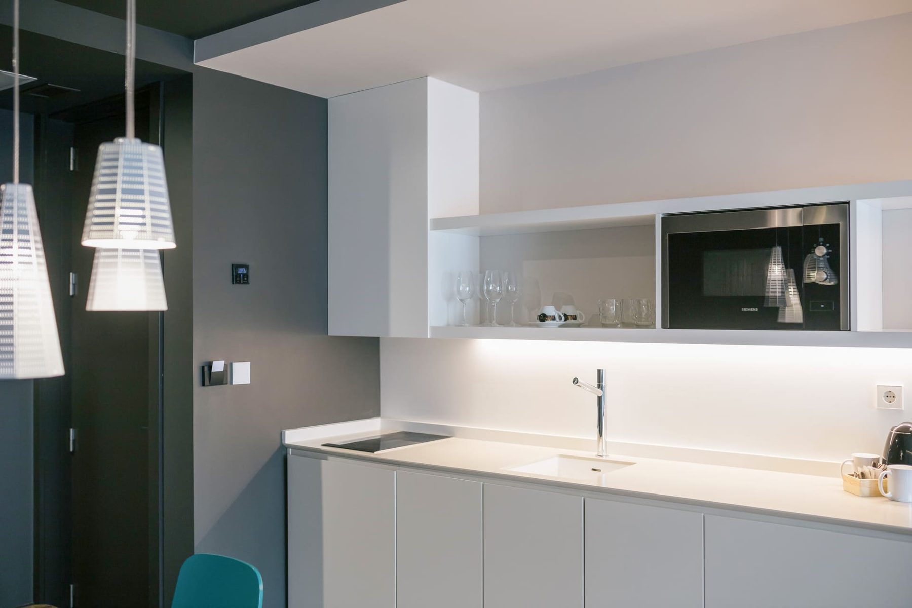 White kitchen cabinets, sink, hob and microwave in a Plaza Mercado room.