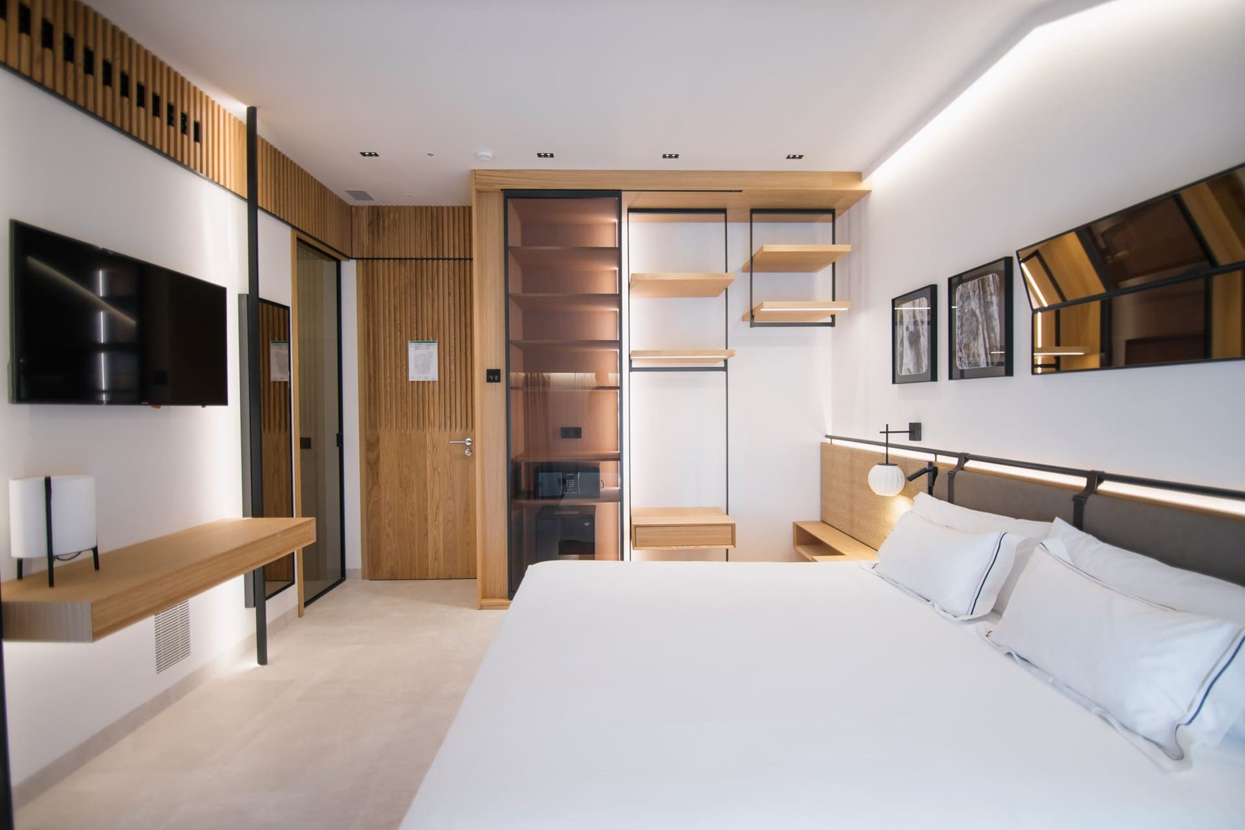 Bed, pale wood shelving and a wall-mounted television in a Puerta Serranos Double Exterior room.