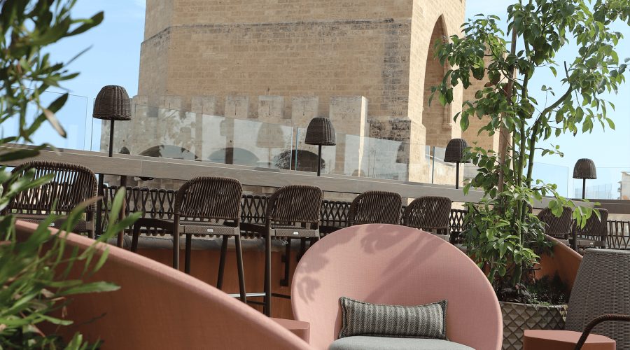 Terrace chairs, bar stools and planting with the stone Serranos Towers behind.
