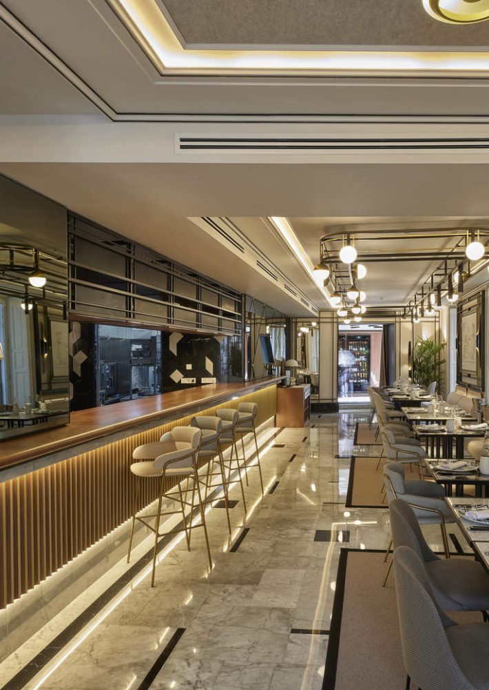 Long gold-toned bar, stools and dining tables inside La Perfumería.