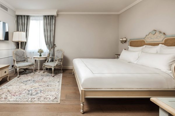 Premium bedroom with carved headboard and window-side chairs at Domus Zamittello.