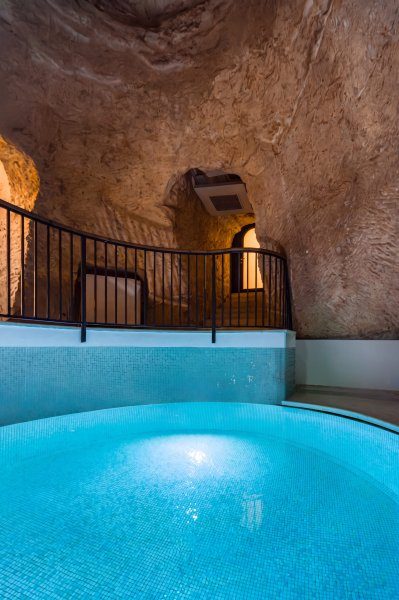 Small blue-tiled indoor pool beneath rough stone walls at La Falconeria.