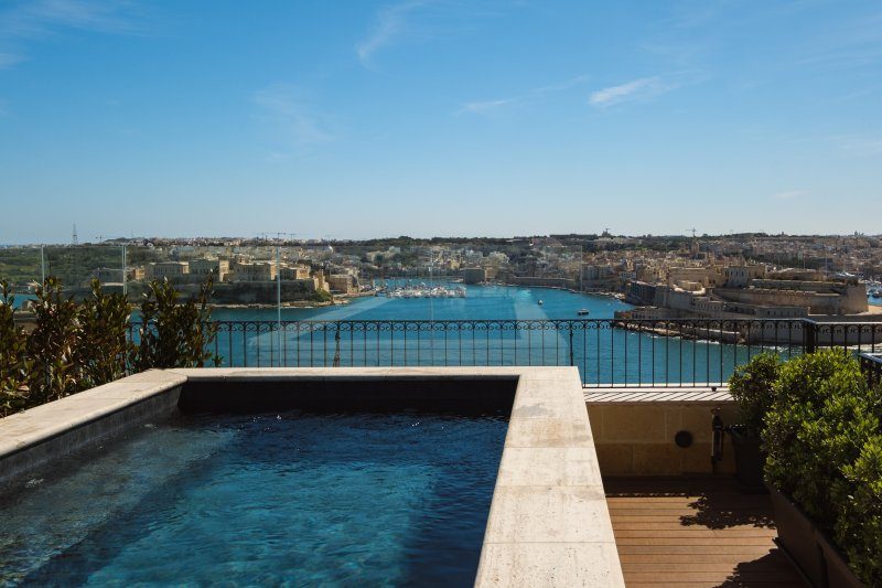 Rooftop pool and deck with Grand Harbour beyond at The Gomerino.
